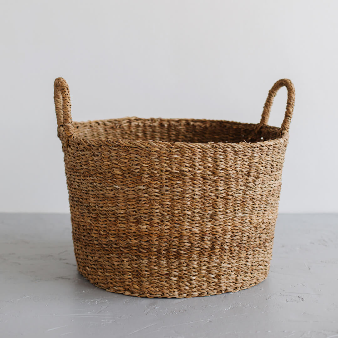The Harvest round base laundry basket is handcrafted from hogla grass, an aquatic plant. Woven together, it creates a design that's both lightweight and strong, with layers of natural texture and tone.