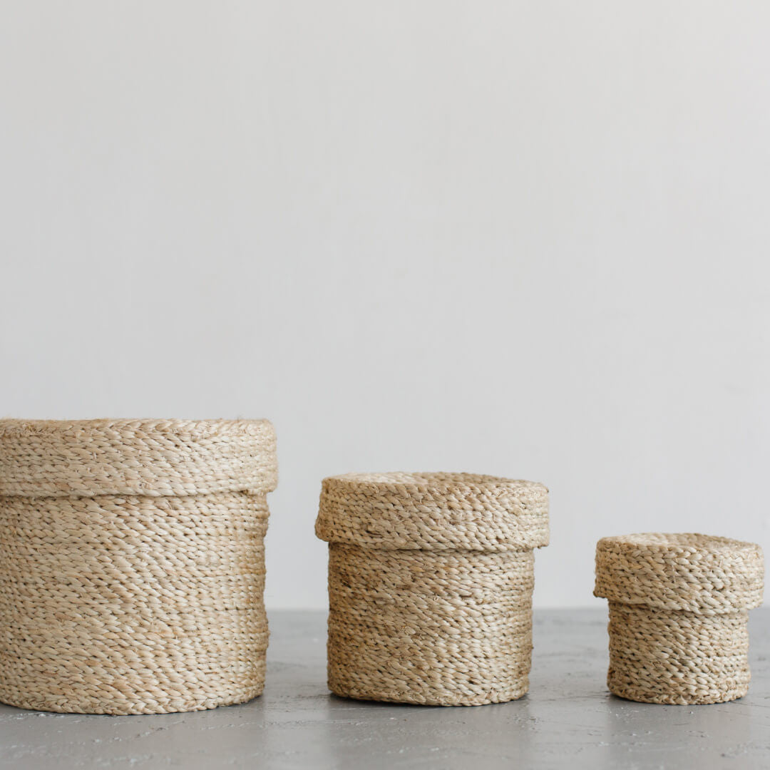 Set of 3 lidded round jute baskets with natural tones and texture compliment an array of design aesthetic. Storage with style in three sizes.