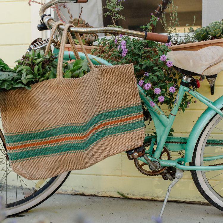 Eco-friendly jute tote bag with reinforced handles, perfect for groceries, beach items, and everyday essentials. The Baja Wide Market Shopper features a chic green and red stripes on natural.