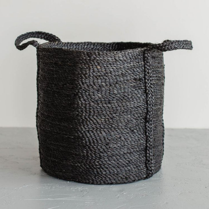 Handcrafted round jute laundry basket in charcoal, perfect for storing and transporting laundry, blankets, towels and other household items.