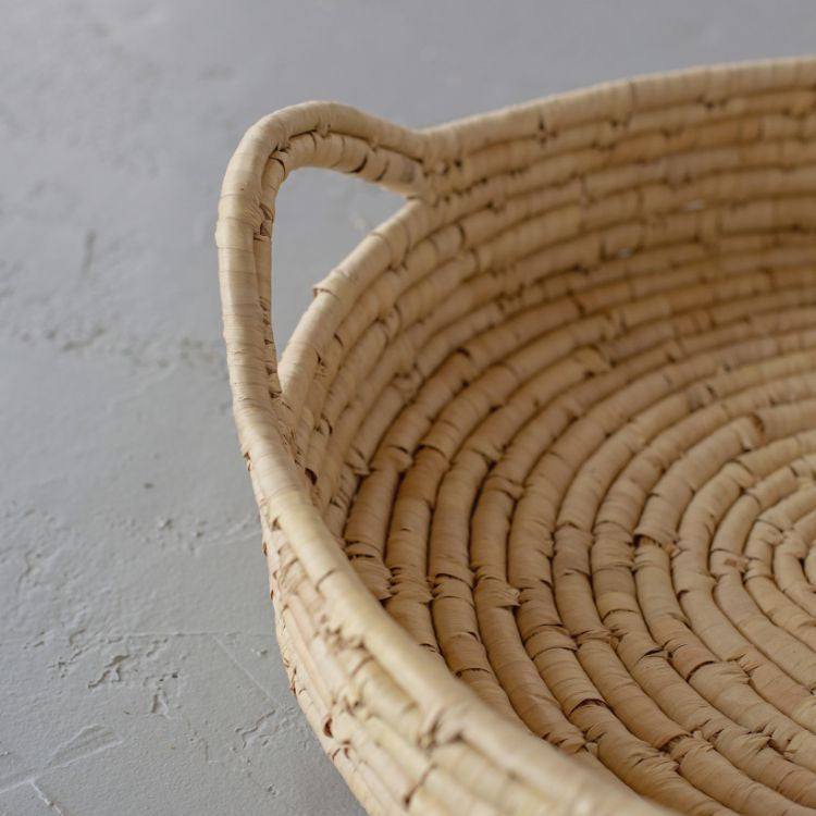 Handwoven palm leaf tray with coiled design, perfect for displaying natural decor at gatherings.