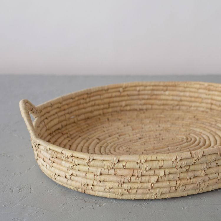Handwoven palm leaf tray with coiled design, perfect for displaying natural decor at gatherings.