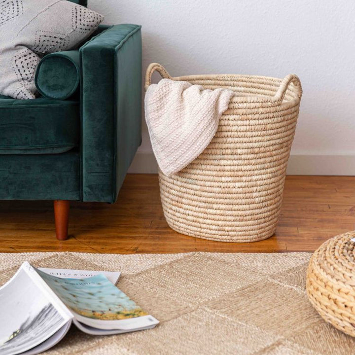 Handwoven palm leaf laundry basket with sturdy handles and natural texture, available in oval or round shape, a versatile and stylish storage solution for any space.