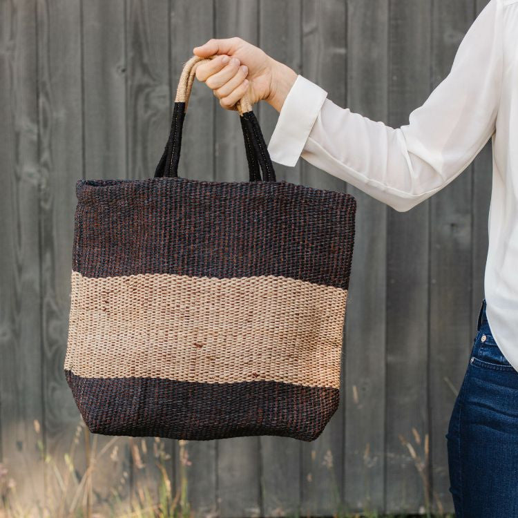 Eco-friendly jute tote bag with reinforced handles, perfect for groceries, beach items, and everyday essentials. The Soho Market Jute Shopper features a chic black and natural color block design, by Will & Atlas.