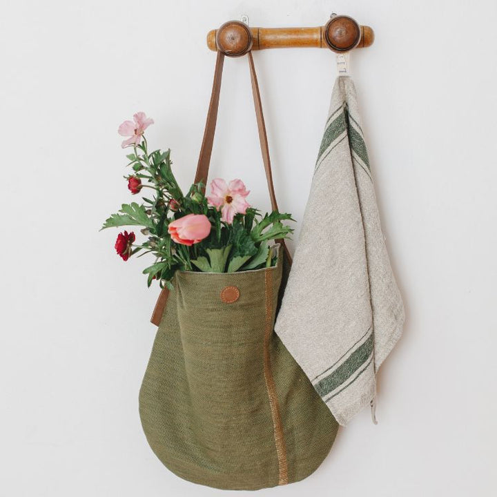 The Archer Jute Tote Bag in olive, a gorgeous accessory, with a jute canvas exterior and interior cotton lining, along with a strong, leather handle it's perfect for everyday use or trips to the farmer's market.