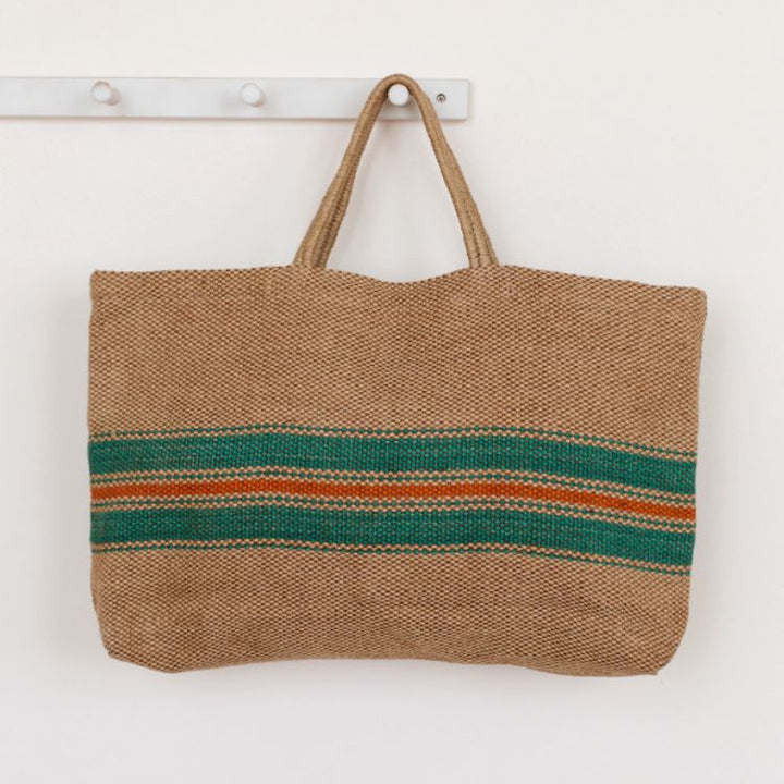 Eco-friendly jute tote bag with reinforced handles, perfect for groceries, beach items, and everyday essentials. The Baja Wide Market Shopper features a chic green and red stripes on natural.