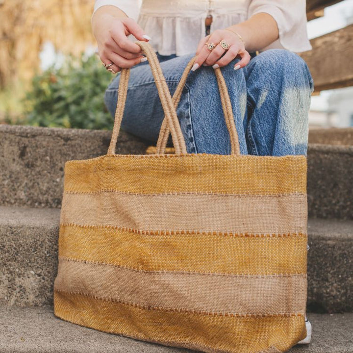 Eco-friendly gold and natural jute tote bag with reinforced handles, perfect for groceries, beach items, and everyday essentials. The Khari Market Shopper are hand woven with traditional techniques and are stylish and practical.