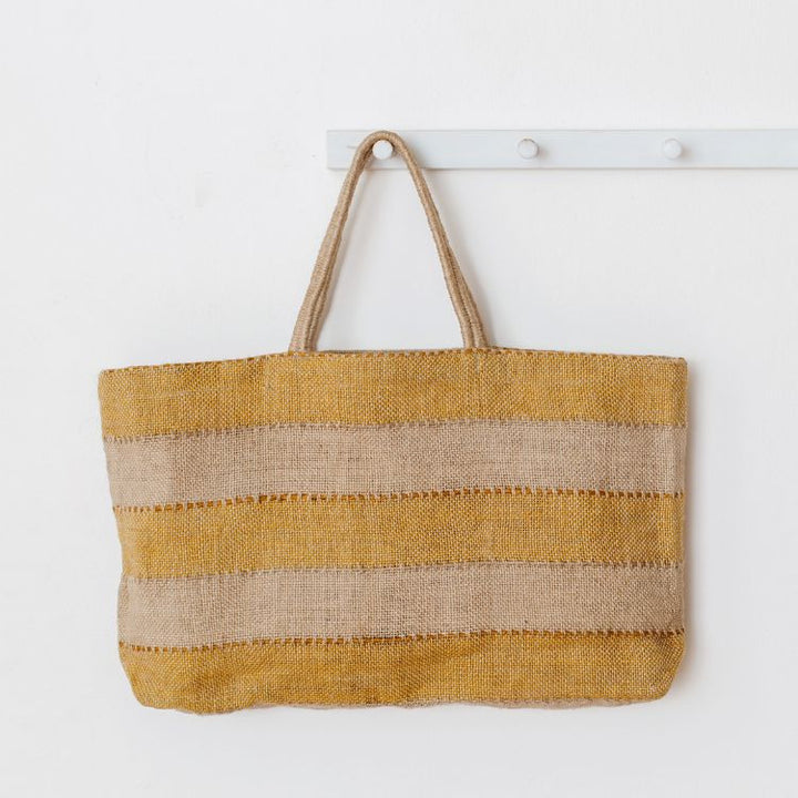 Eco-friendly gold and natural jute tote bag with reinforced handles, perfect for groceries, beach items, and everyday essentials. The Khari Market Shopper are hand woven with traditional techniques and are stylish and practical.