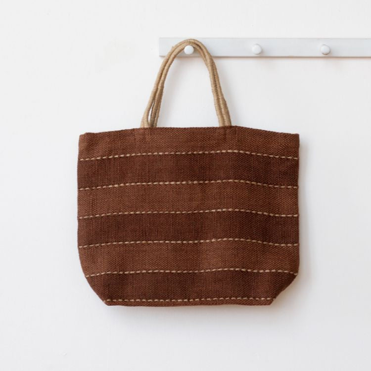 Eco-friendly coffee colored jute tote bag with reinforced handles, perfect for groceries, beach items, and everyday essentials. The Khari Market Shopper are hand woven with traditional techniques and are stylish and practical.