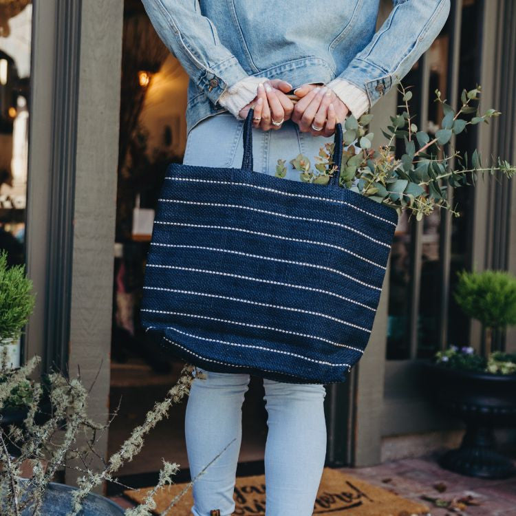 Handcrafted Marin jute shopper bag in slate grey or indigo with striped detailing and a woven, colorblocked handle, made using natural dyes and eco-friendly jute fibers from Bangladesh.