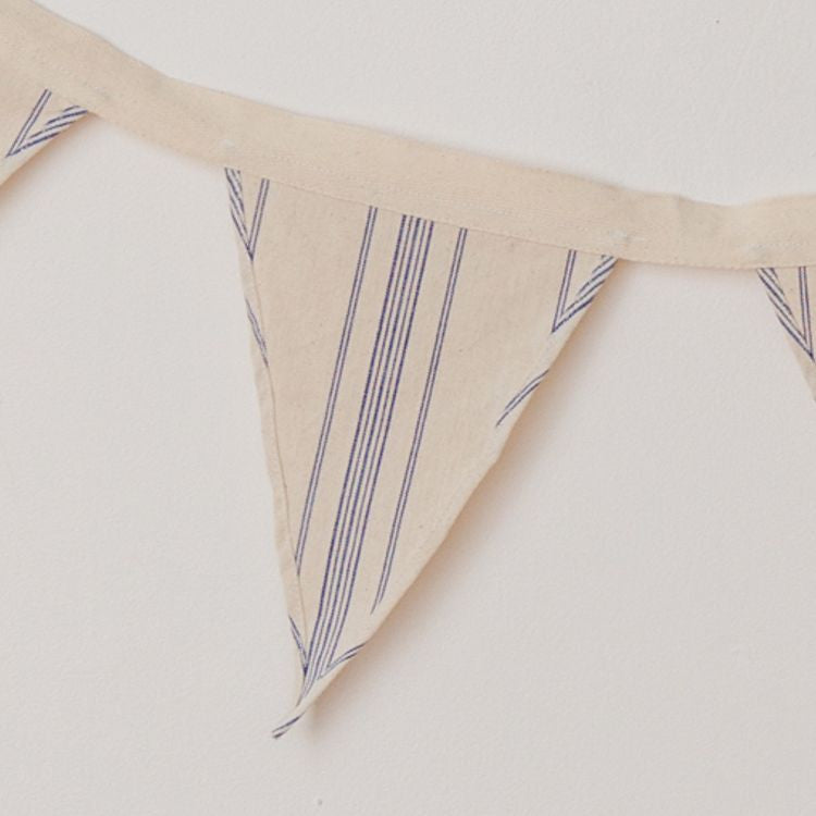 Handwoven natural cotton bunting with blue stripes, perfect for adding a whimsical touch to any space or soiree. Use to decorate your nursery or playroom, or display out in the garden for a picnic or birthday party.