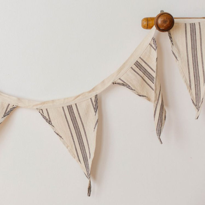 Handwoven natural cotton bunting with black stripes, perfect for adding a whimsical touch to any space or soiree. Use to decorate your nursery or playroom, or display out in the garden for a picnic or birthday party.