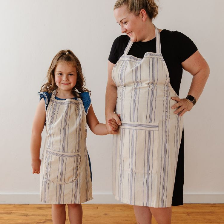 Handwoven natural cotton ticking stripe apron with center pocket and generous length, perfect for culinary adventures and available in both adult and child sizes.