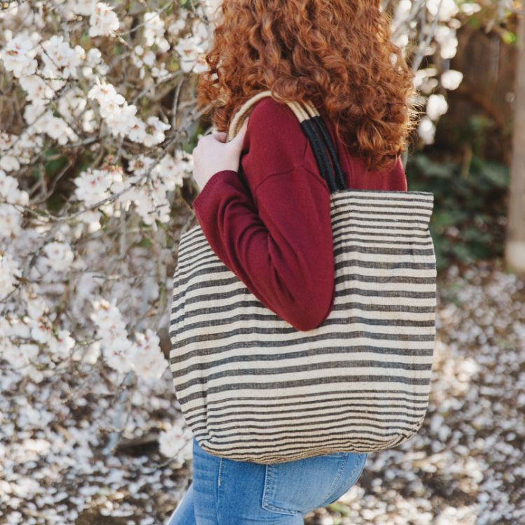 Paloma striped shopper with durable suede handles and zipper closure. Available in black or indigo striped detailing and natural jute fiber. Stylish and versatile accessory from Will & Atlas.