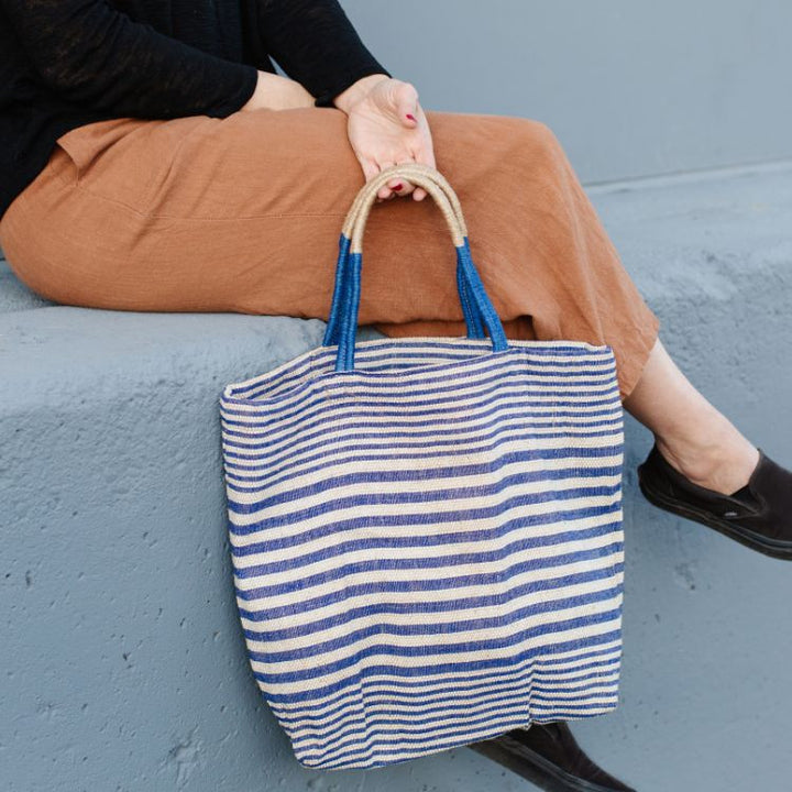 Paloma striped shopper with durable suede handles and zipper closure. Available in indigo striped detailing and natural jute fiber. Stylish and versatile accessory from Will & Atlas.