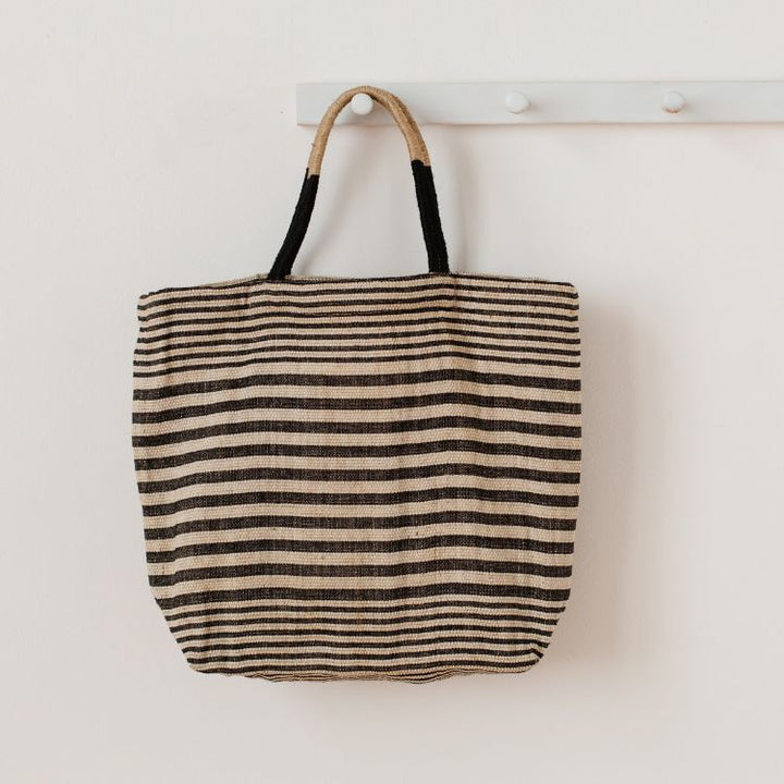 Paloma striped shopper with durable suede handles and zipper closure. In black striped detailing and natural jute fiber. Stylish and versatile accessory from Will & Atlas.