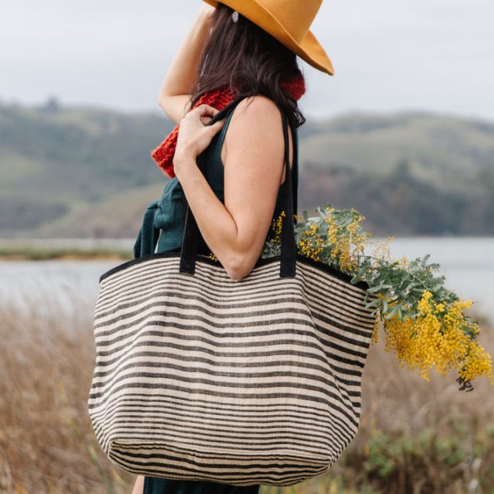 Spacious Paloma Collection striped totes with durable suede handles and zipper closure. Available in black or indigo striped detailing and natural jute fiber. Stylish and versatile accessory from Will & Atlas.
